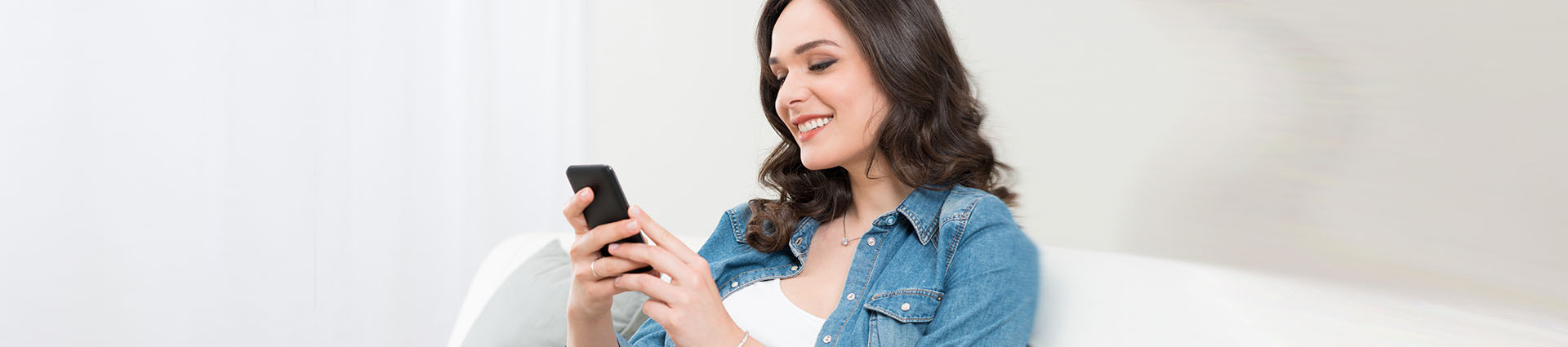 woman using phone sitting on couch