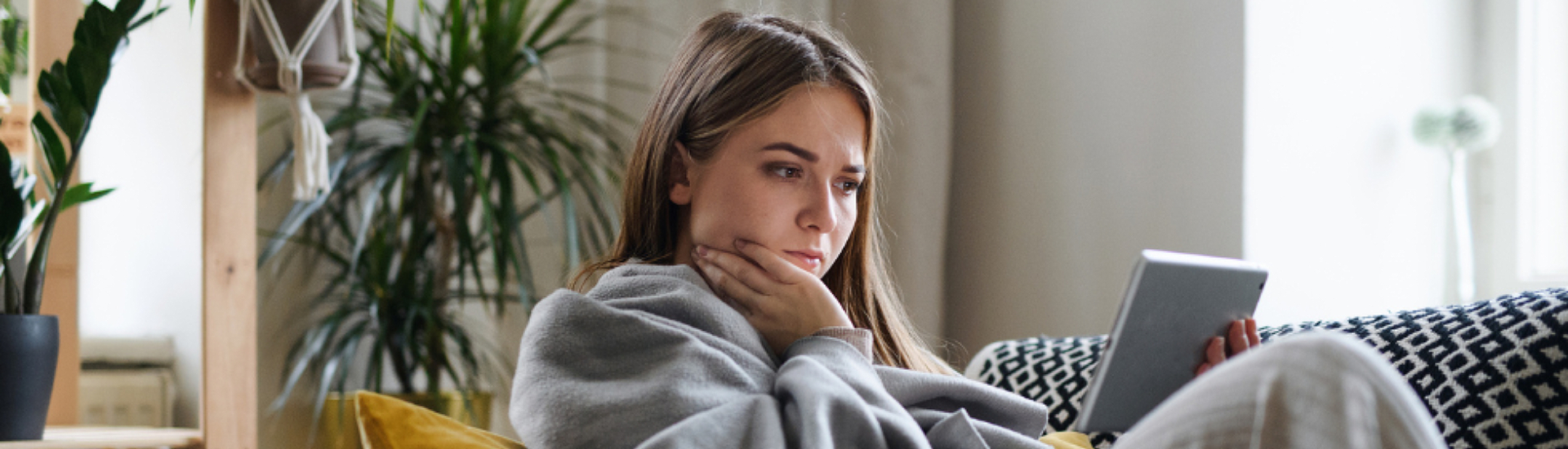 woman on couch using blanket and tablet
