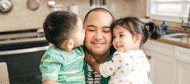 father and children hugging in kitchen